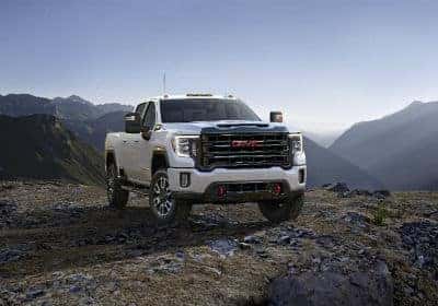 2020 GMC Sierra AT4 exterior front fascia and passenger side on hill with mountains in distance