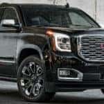 2019 GMC Yukon Denali exterior front fascia and passenger side in front of old white wall