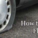 Close up of a flat tire on a car with the text "How to change a flat tire"