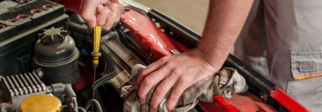 Mechanic using the dipstick to check the oil in a car engine