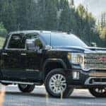 2020 GMC Sierra Denali exterior front fascia and passenger side on road with pine trees