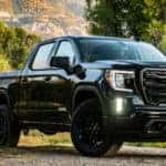 2020 GMC Sierra Elevation exterior front fascia and passenger side in front of tree grassy hill