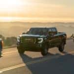 2020 GMC Sierra lineup exteriors front fascia and driver side on highway overlooking mountains