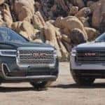 Two GMC Acadia parked next to each other before a mountainous background