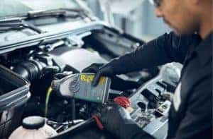 a man pouring an oil into an engine