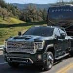 A new 2022 GMC Sierra HD towing a large trailer down a rural highway