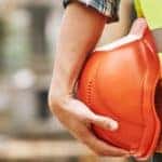 a person holding an orange hard hat