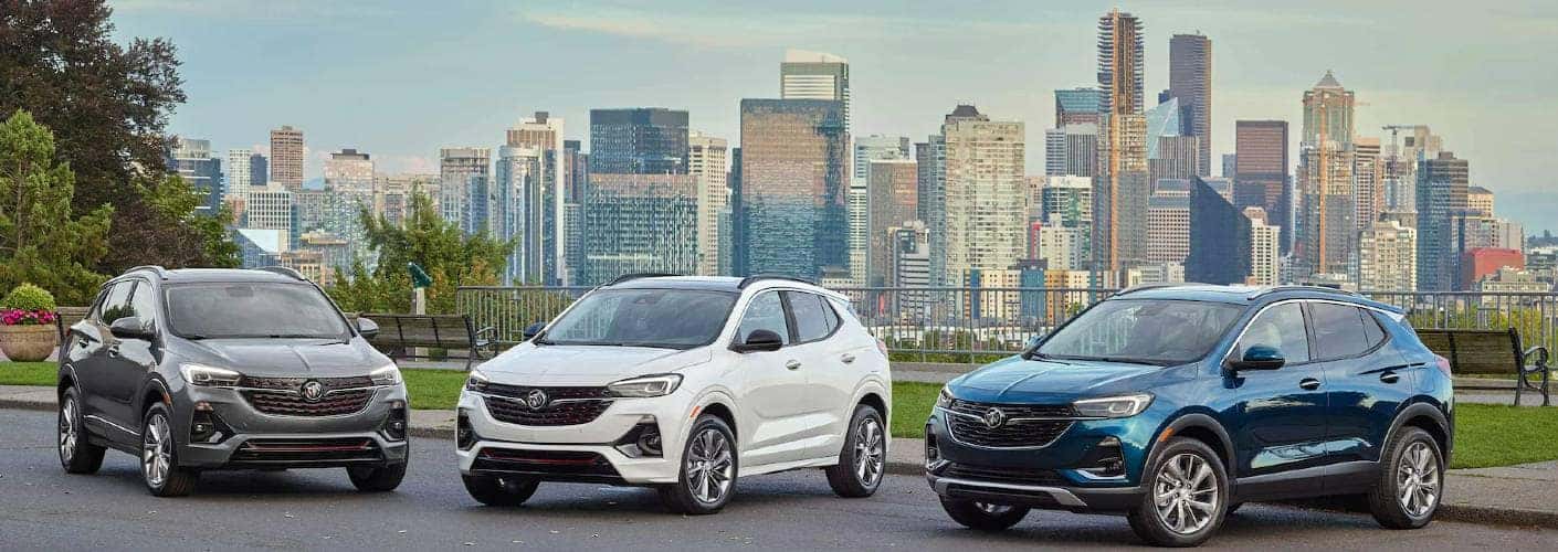 Three different colored 2022 Buick Encore GX models parked in front of a city skyline.