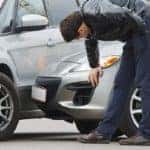 Two people inspecting two crashed cars
