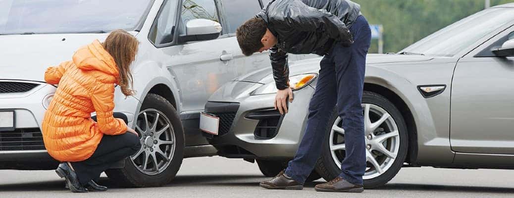 Two people inspecting two crashed cars