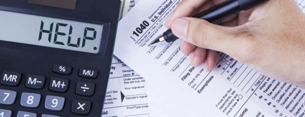 A hand holding a pen to a tax document