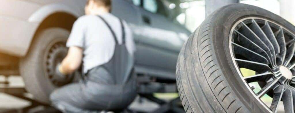 a man crouching by a car replacing its tire