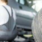 a man crouching by a car replacing its tire