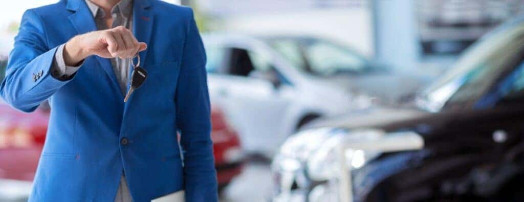 a person holding a car key at a dealership