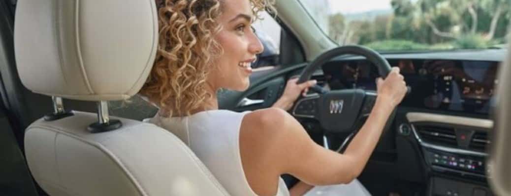 a woman with both her hands on a steering wheel of a Buick