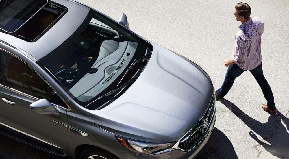 A man walking towards a silver 2019 Buick Enclave in a parking lot