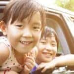 Children and their father with heads out the window of a car
