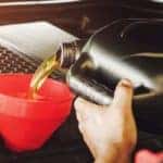 A mechanic pouring oil into a car engine