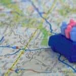 A map with a toy van carrying little pieces of plastic indicating passengers