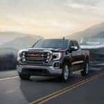 2020 GMC Sierra 1500 driving down the road at sunrise, towing a trailer