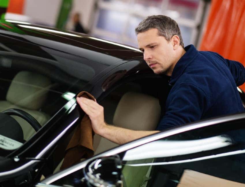 A mechanic polishing the door frame of a car