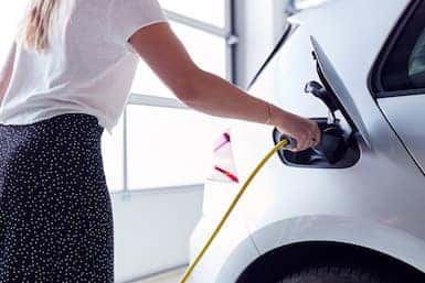 woman charging electric vehicle at home