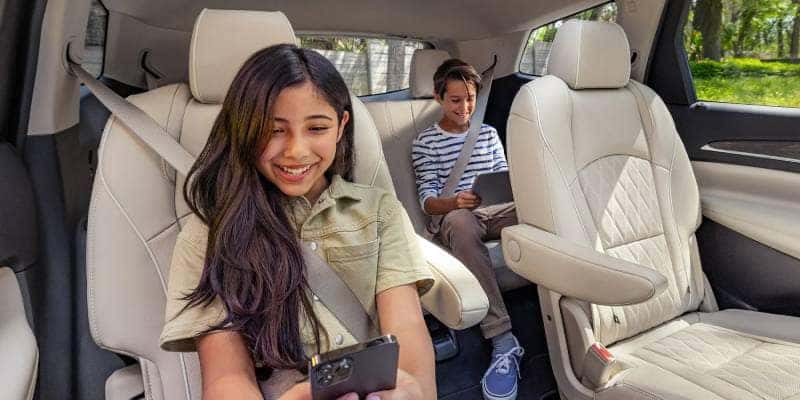 Kids enjoying the technologically advanced connectivity features inside the 2022 Buick Enclave.