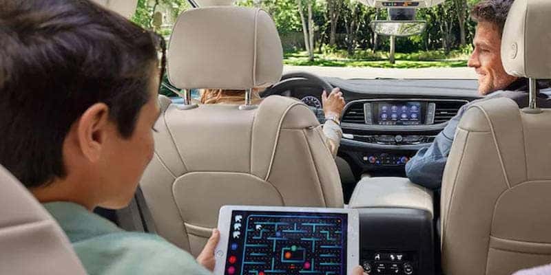 Kids sitting in the 2nd row of the 3 row 2023 Buick Enclave SUV, while enjoying the available WiFi hotspot.