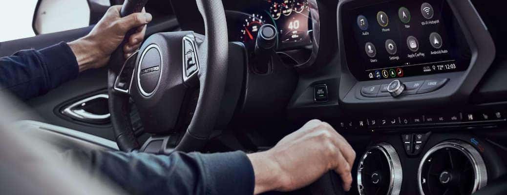 A man using the manual shifter available in the 2023 Chevy Camaro, which has excellent performance features.