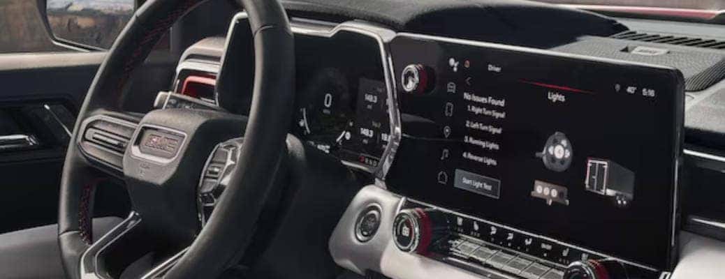 The large infotainment center and digital instrument cluster in a GMC truck.