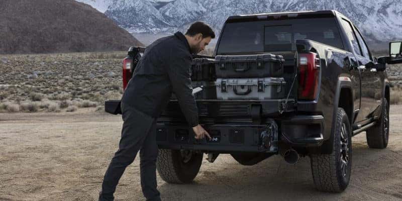 A man loading cargo into the 2024 GMC Sierra 2500 HD.