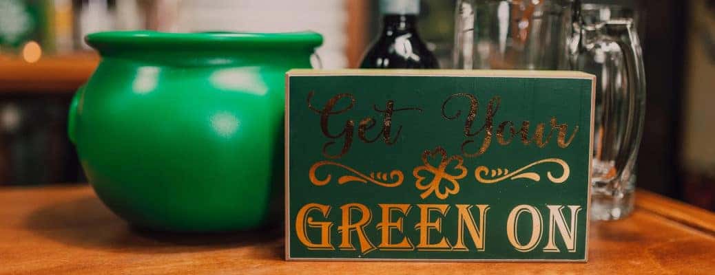 A St. Patrick's Day sign near some mugs and a pot of gold.