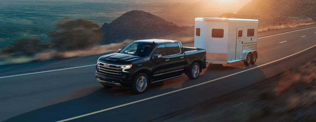 The 2024 Chevy Silverado 1500 demonstrating its cargo and towing capabilties on the road.