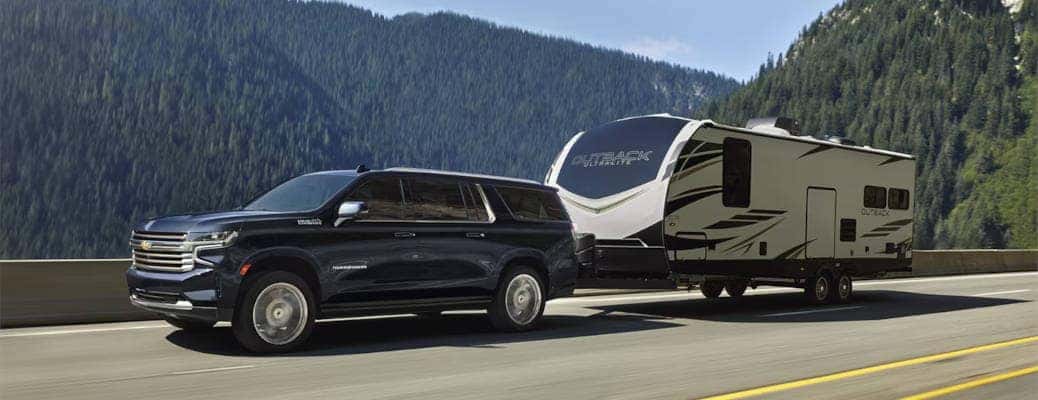 The 2024 Chevy Suburban towing a large camper trailer.