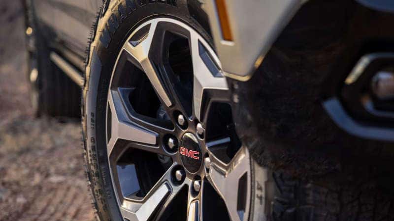 A closeup of the grille and front wheel of the 2025 GMC Yukon.