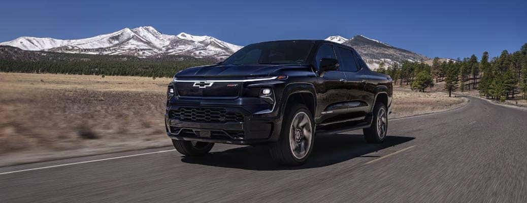 The long-range 2025 Chevy Silverado EV driving on a rural highway.