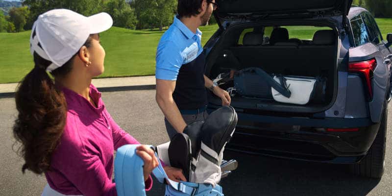 People loading golf equipment into the cargo area of the Blazer EV