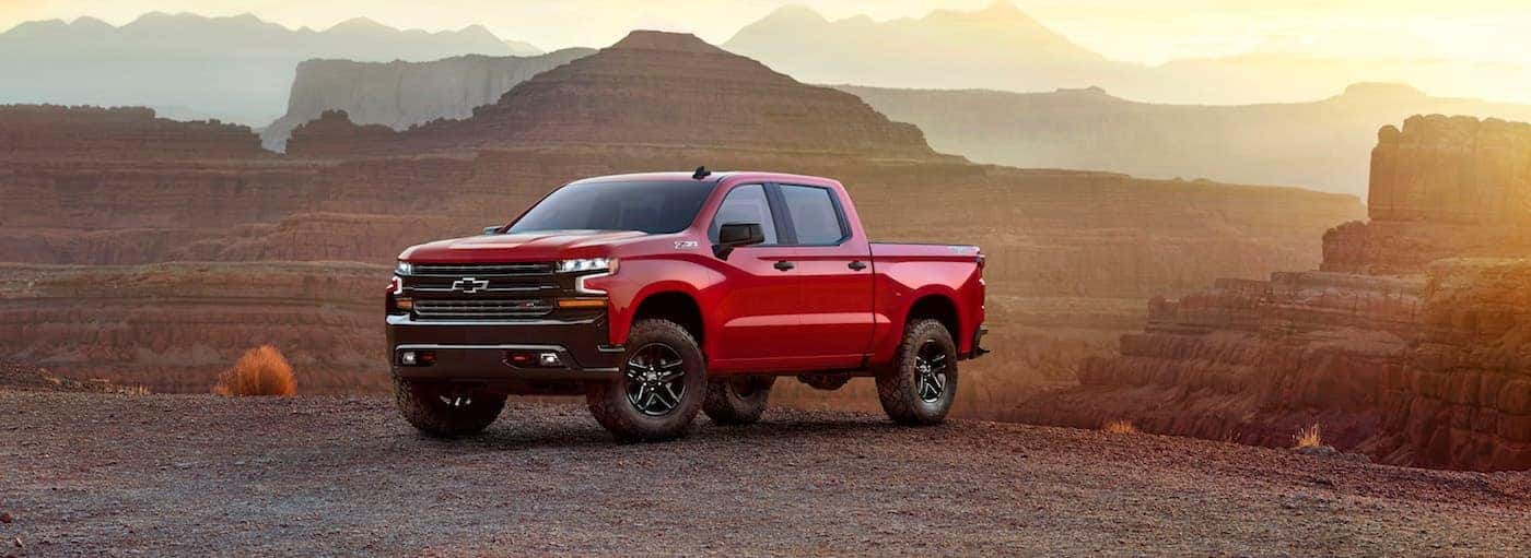 A red 2019 Chevy Silverado stands majestically in front of a mountain range at sunset