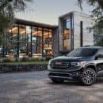 A black 2019 GMC Acadia All Terrain in front of a modern mansion
