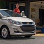 woman getting in driver's seat of silver 2019 Chevrolet Spark