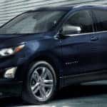 Blue 2020 Chevy Equinox, exterior side/front view, parked in a futuristic garage.