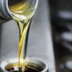 Oil pours from a container into a waiting engine