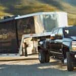 2019 Chevy Silverado HD pulls a very large trailer up a curving highway.