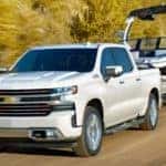 White 2020 Chevy Silverado tows a boat along a mountain ridge.