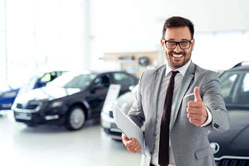 Salesman in a dealership happily gives the "thumbs up"