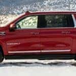 Side view of a red 2021 GMC Yukon in the snow