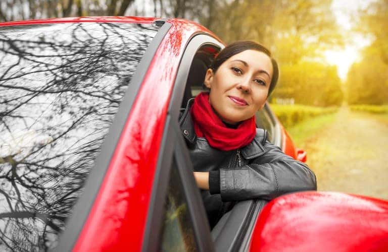 a woman driving a red car with her head out the window