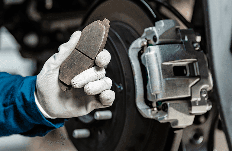a white-gloved hand holding a vehicle brade pad