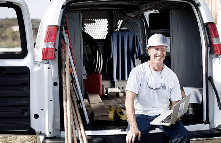 2023 GM work vehicle with a man leaning on the tailgate