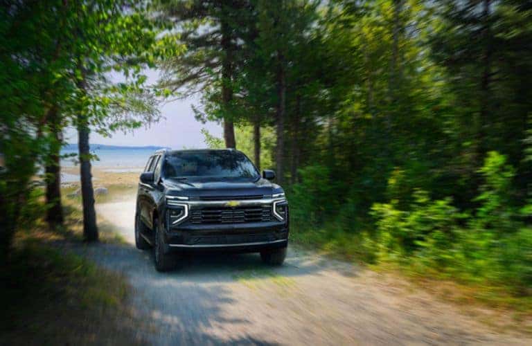 2025 Chevrolet Tahoe driving on a gravel trail through trees